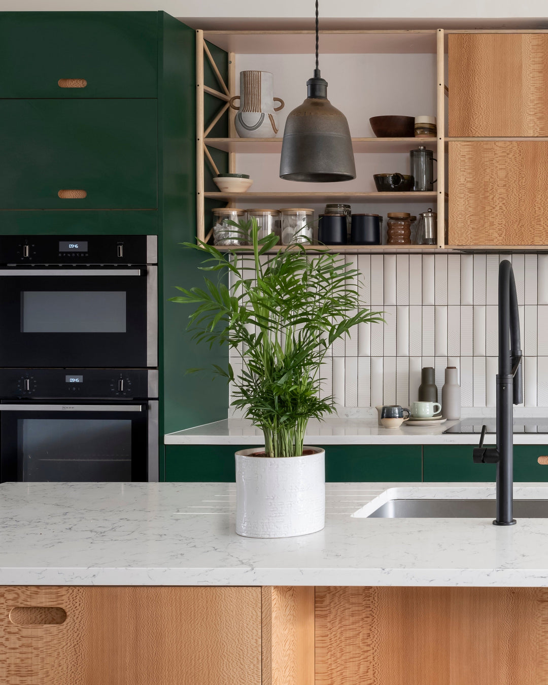 Modern kitchen with green cabinets, wooden island, and white countertops.