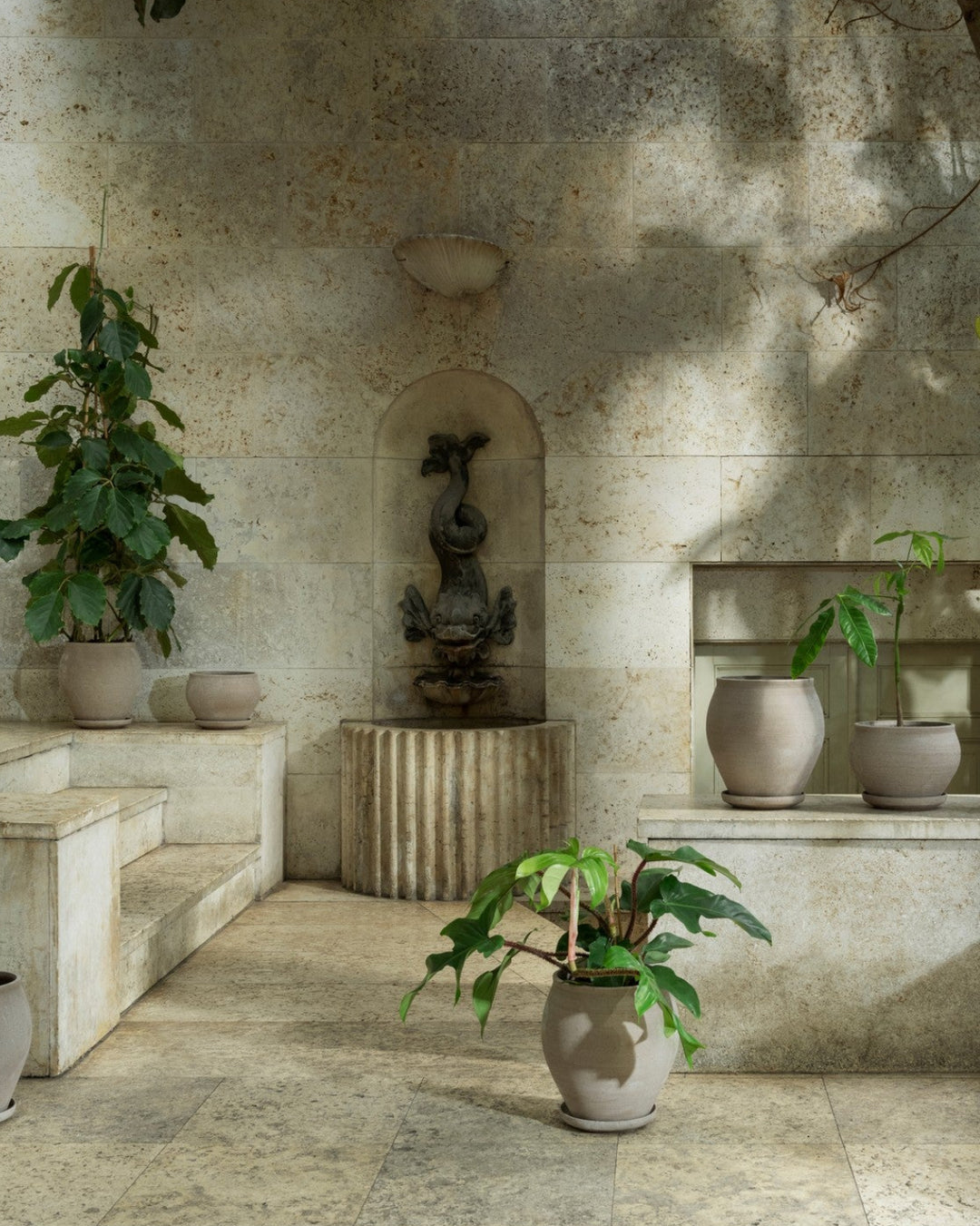 Patio with stone walls, potted plants, and a small fountain.