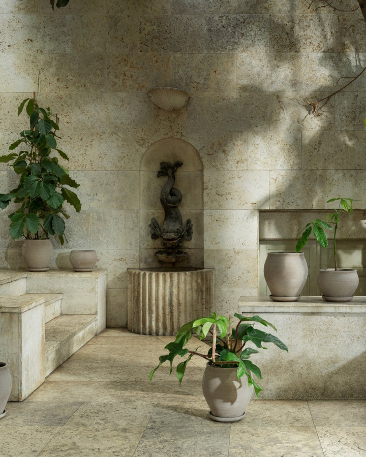 Patio with stone walls, potted plants, and a small fountain.